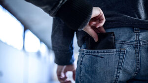 Osoba próbuje wyciągnąć portfel z tylnej kieszeni spodni mężczyzny.