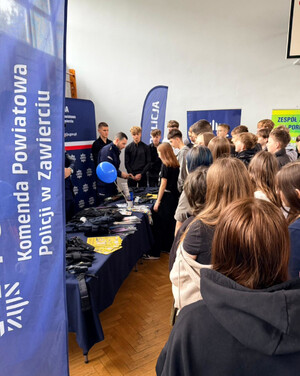 Policjanci przy stoisku profilaktycznym, prezentują uczniom policyjny sprzęt.