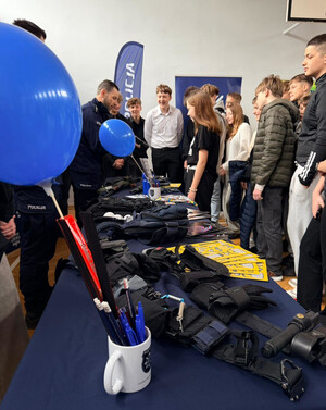 Policjanci przy stoisku profilaktycznym, prezentują uczniom policyjny sprzęt.