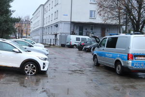 Parking, na którym widać zaparkowane samochody oraz radiowóz.