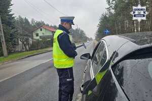 Policjant podczas kontroli drogowej rozmawia z kierującym samochodem.