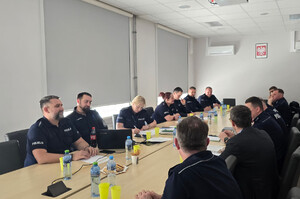 Widoczni policjanci siedzący przy stole w sali narad.