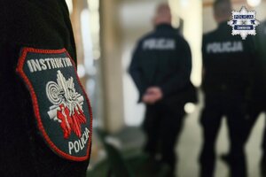 Widoczna naszywka na policyjnym mundurze. Na naszywce widoczny napis: Instruktor, Policja. W tle policjanci.