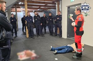 Ratowniczka medyczna prezentuje maski do sztucznego oddychania policjantom.