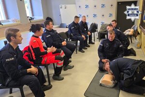 Policjanci ćwiczą na fantomach. Przygląda się im ratowniczka medyczna oraz inni funkcjonariusze.