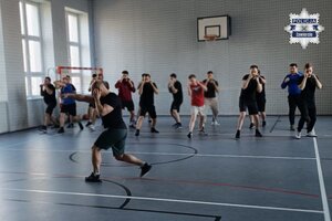 Nieumundurowani policjanci ćwiczą na sali gimnastycznej.