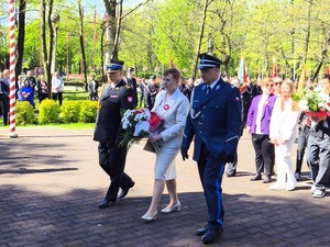 Delegacja z kwiatami podchodząca do pomnika. Wśród delegatów policjant.