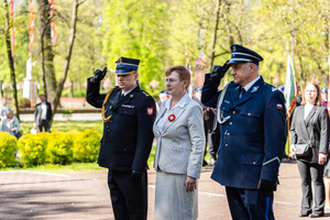 Delegacja przed pomnikiem, oddaje honor. Wśród delegatów policjant.