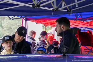 Policjant rozmawia z osobami obecnymi przy stoisku profilaktycznym. Zdjęcie: kapitan Grzegorz Nowak. Powiatowa Państwowa Straż Pożarna w Zawierciu.