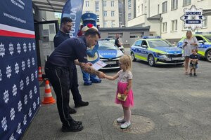 Dziewczynka odbiera od policjanta dyplom.