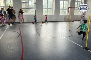 Dzieci i opiekunowie na sali gimnastycznej.