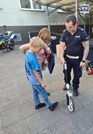 Policjant prezentuje chłopcu miernik odległości.