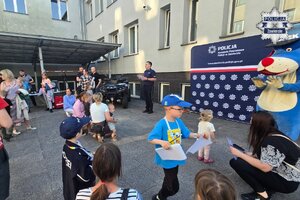 Sznupek, policjant rozdający dyplomy oraz dzieci i opiekunowie.