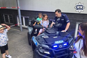 Dziewczynka i chłopczyk na policyjnym quadzie. Obok nich policjant.