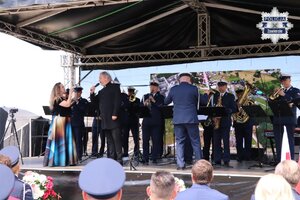 Anita Maszczyk i Leopold Stawarz śpiewają na scenie przy akompaniamencie Orkiestry Komendy Wojewódzkiej Policji w Katowicach.