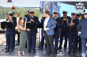 Julia Doległo oraz Bernard Stawarz śpiewają na scenie przy akompaniamencie Orkiestry Wojewódzkiej Policji w Katowicach.