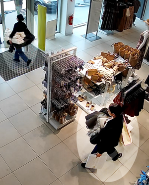 Widoczne dwie kobiety - sprawczynie kradzieży. Jedna wychodzi ze sklepu, a druga idzie w kierunku wyjścia.
