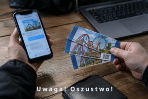 Grafika wygenerowana przez sztuczną inteligencję. Widoczny telefon komórkowy trzymany przez mężczyznę w lewej ręce, a w prawej bilety do parku rozrywki. Na dole napis: Uwaga! Oszustwo!