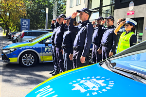 Policjanci oddają honor poległemu na służbie funkcjonariuszowi.