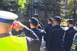 Policjanci oddają honor poległemu na służbie funkcjonariuszowi.