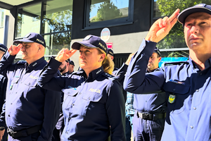 Policjanci oddają honor poległemu na służbie funkcjonariuszowi.