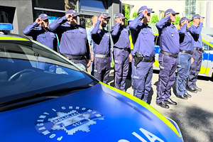 Policjanci oddają honor poległemu na służbie funkcjonariuszowi.